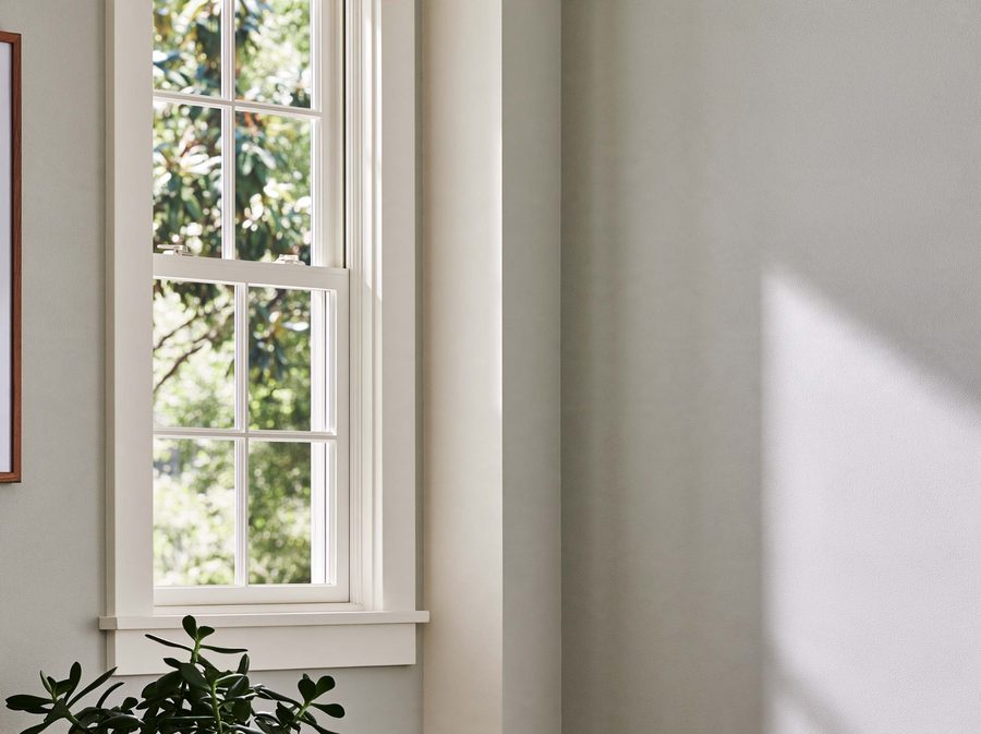 White-trimmed window beside softly textured painted walls.